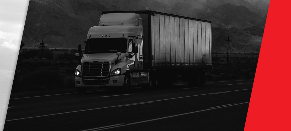semi truck on road with mountains behind, image black and white with red and white trim on ends