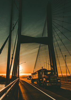 semi truck crossing bridge at sunset