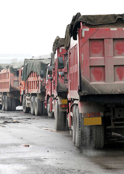 red dump trucks driving in a line