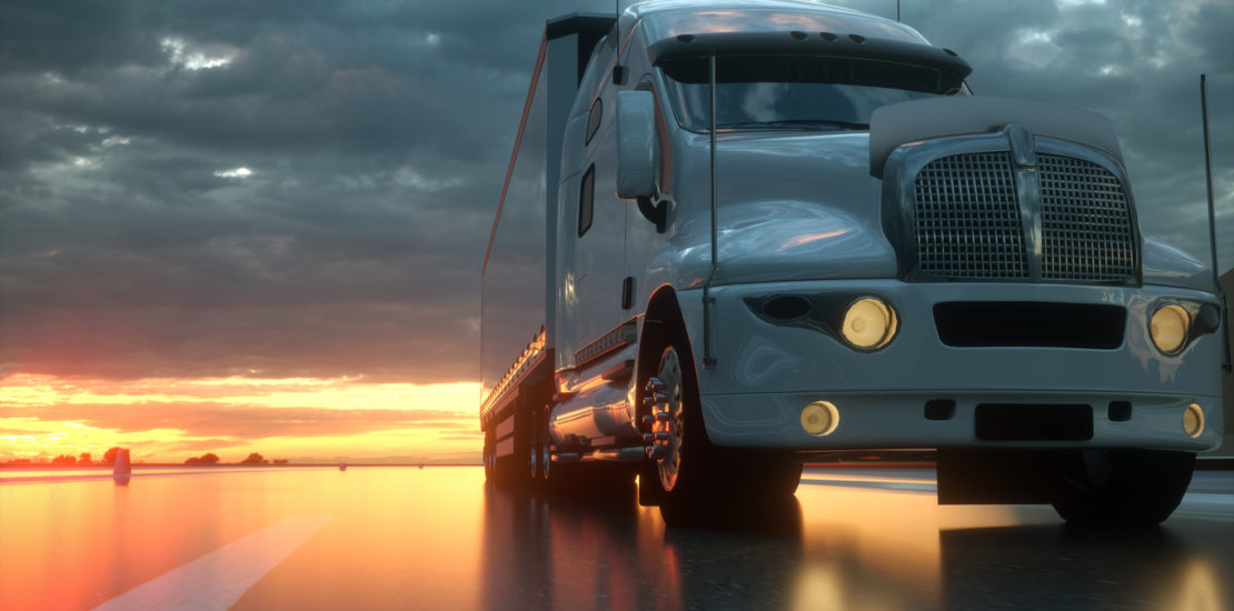 A modern white semi truck parked in front of a colorful sunset.