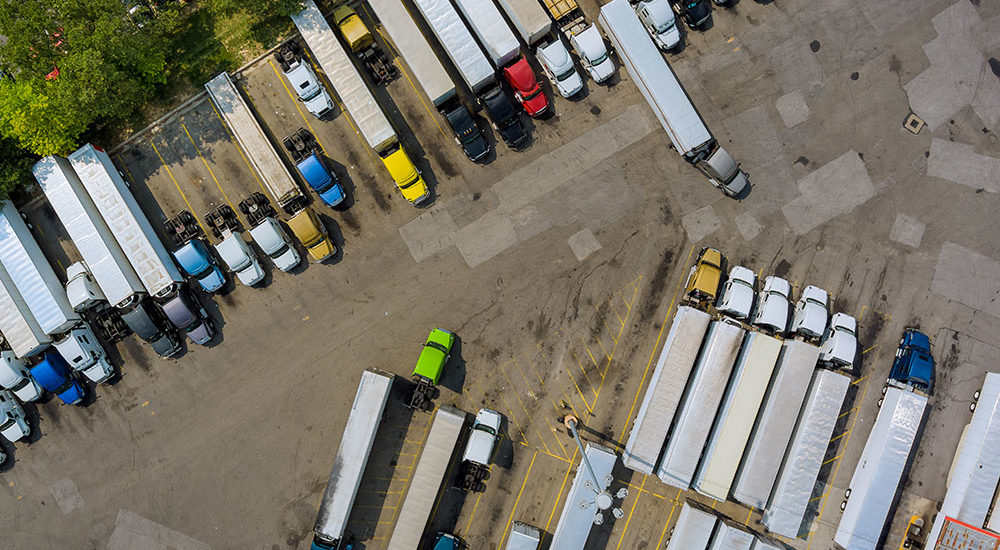 An aerial shot looking down over a parking lot filled with semi trucks.